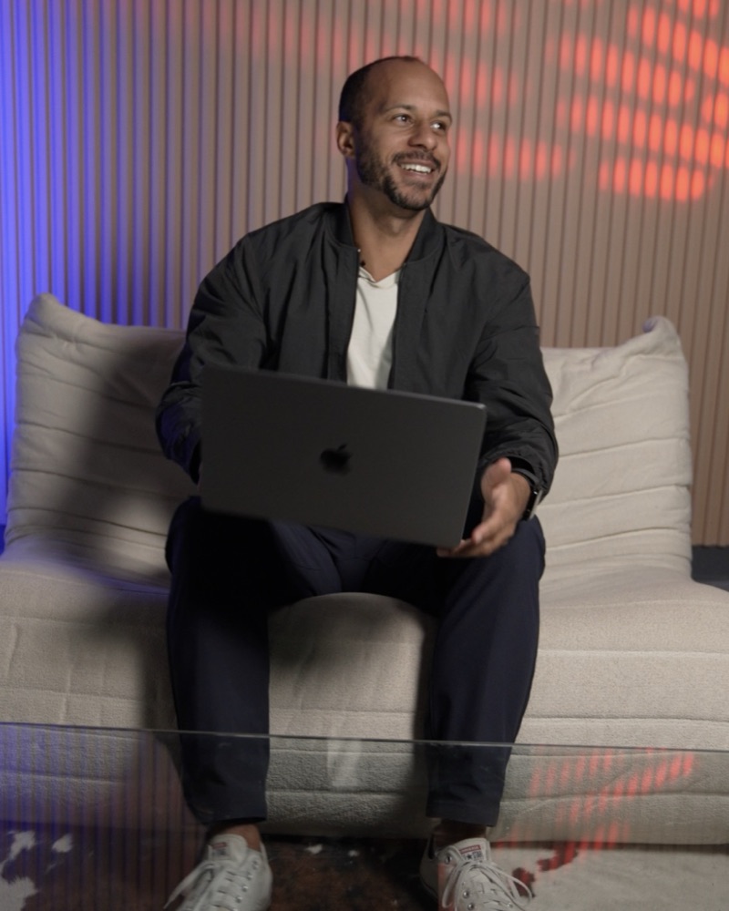 Mike Onuigbo, founder of The Marketing Block, sitting with a laptop